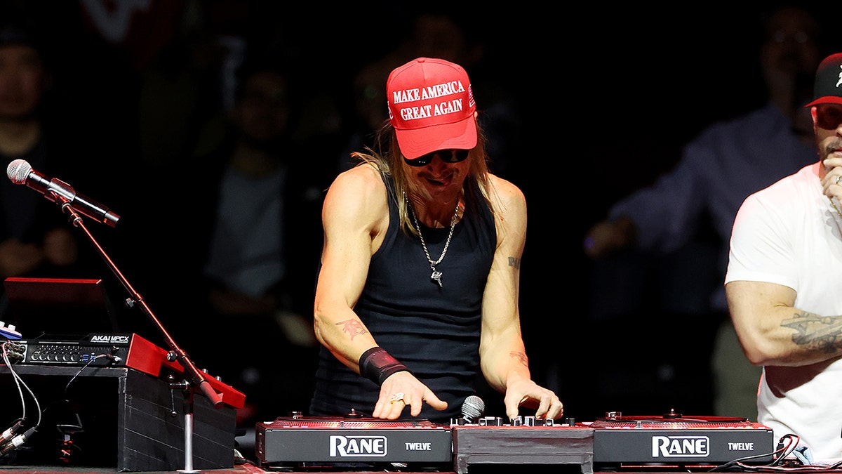 Kid Rock wears a black tank top and a red cap 