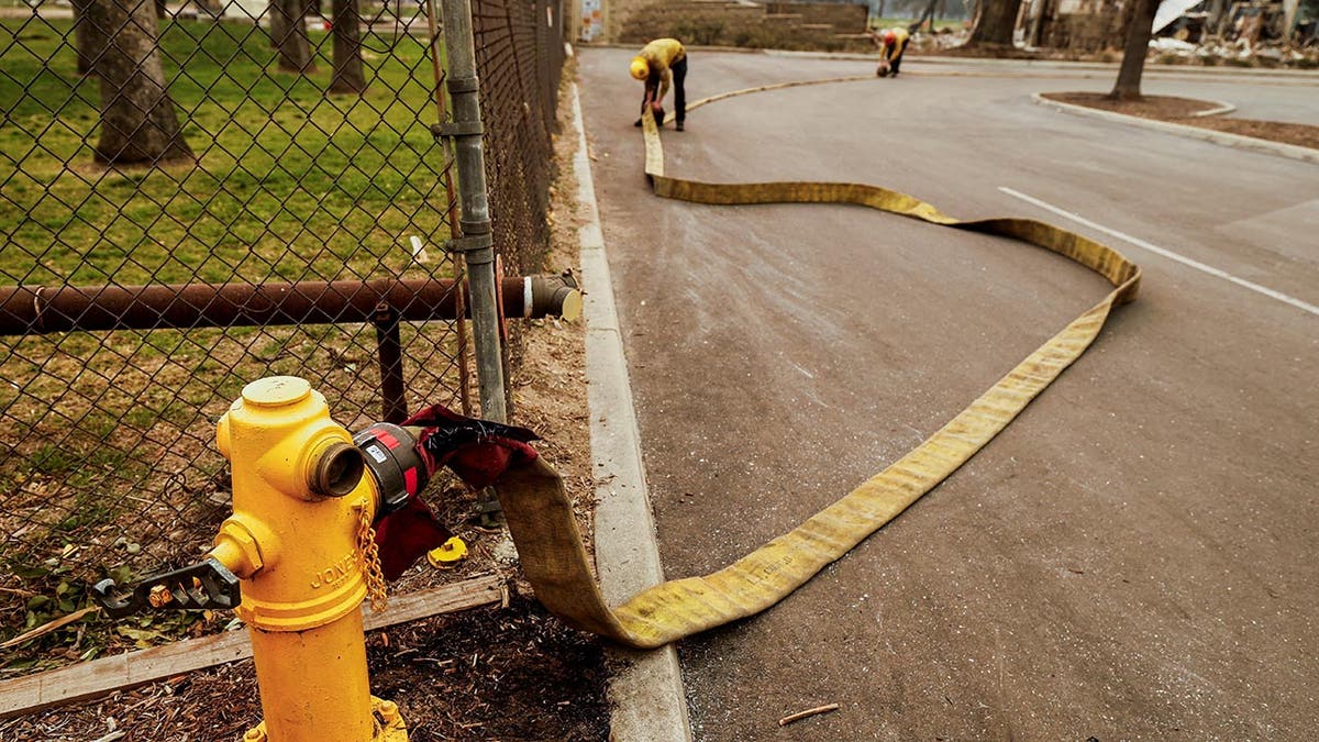 Firefighters roll up a hose used to fight the Eaton Fire after an hydrant run out of water, as powerful winds fueling devastating wildfires in the Los Angeles area force people to evacuate, in Altadena, California, U.S. January 9, 2025.  