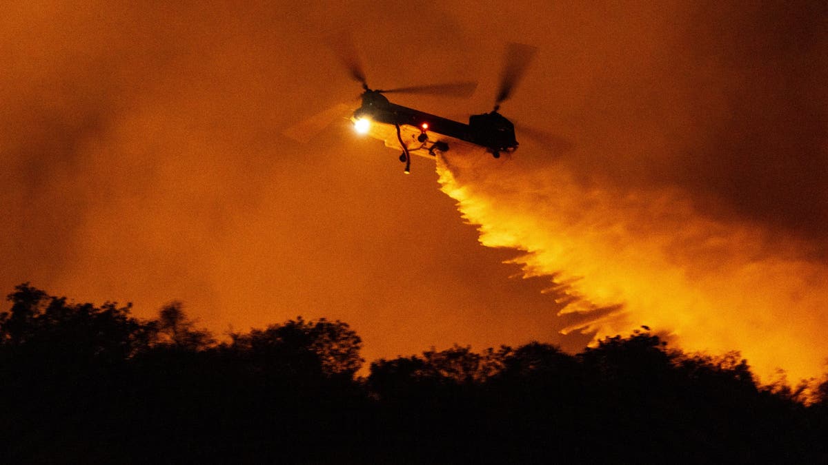 A helicopter drops water to quench the wildfires devastating southern California