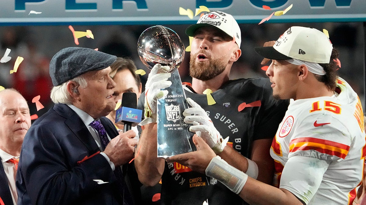 Travis Kelce and Patrick Mahomes pass the trophy