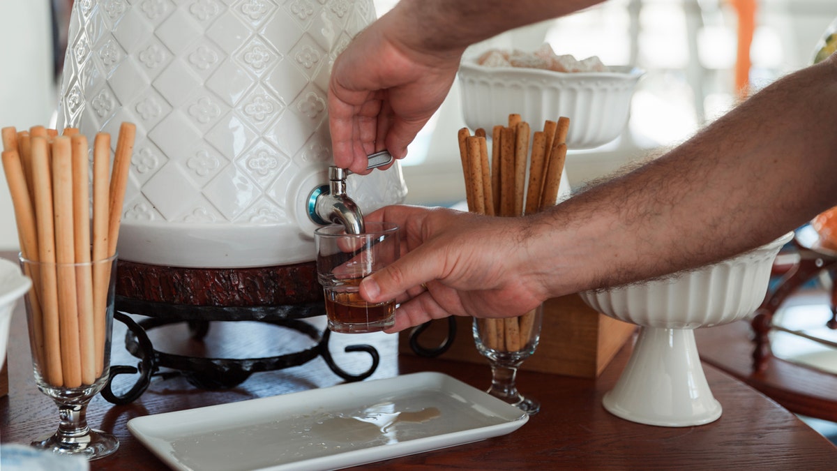 The man pours down his own drinking drink on the table.