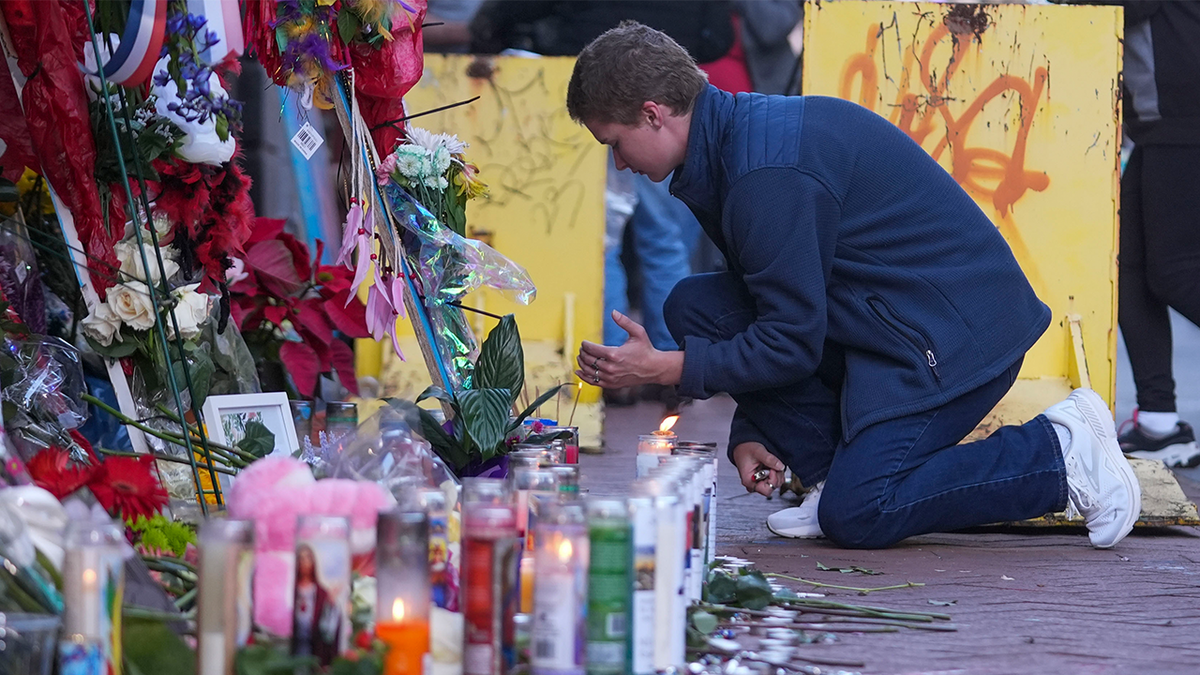 Nathan Williams, a student at the University of New Orleans, lights a candle at the memorial on Bourbon Street