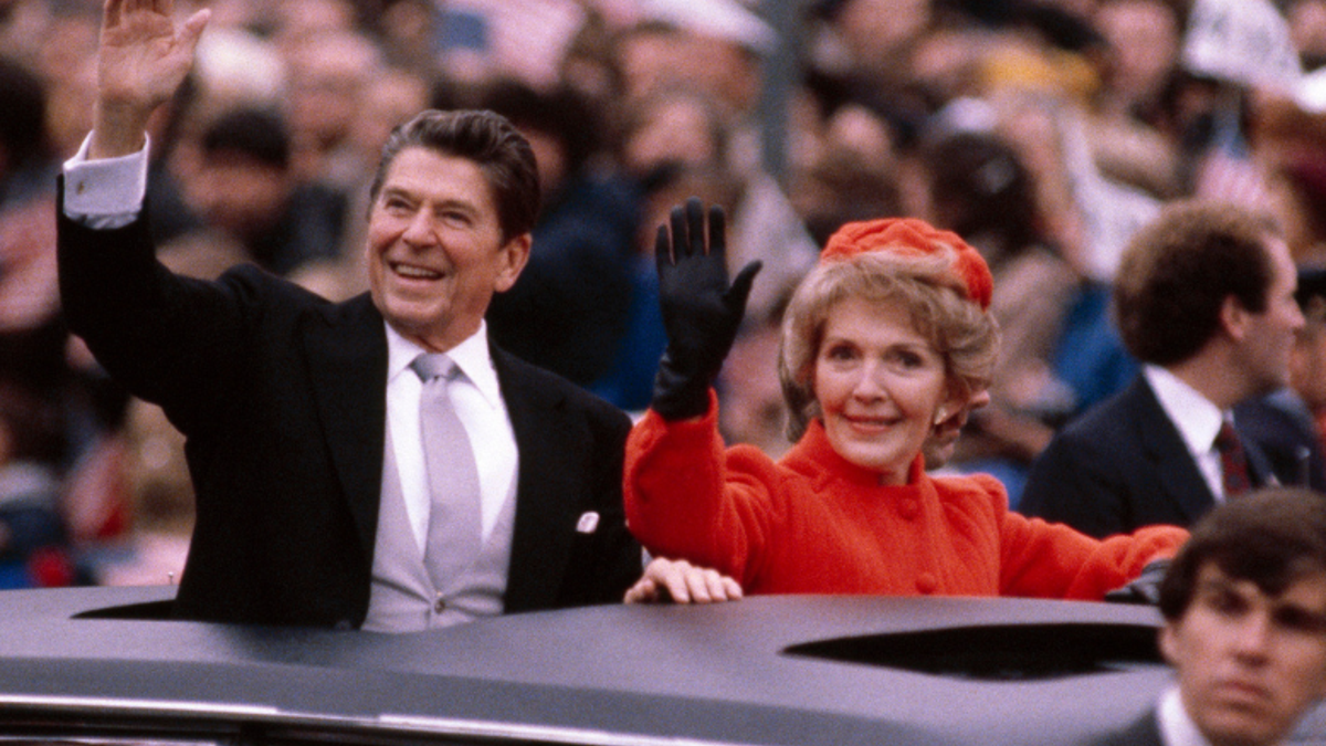 President Ronald Reagan and wife Nancy wave to the crowd from the Presidential Limosine as they ride down Pennsylvania Avenue during the Inaugural parade January 20, 1981 in Washington, DC.