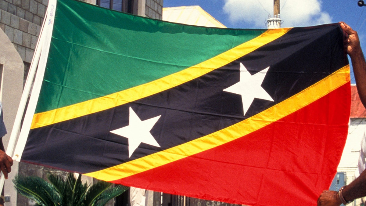 Two men carry St. Kitts and Nevis flag by building the government