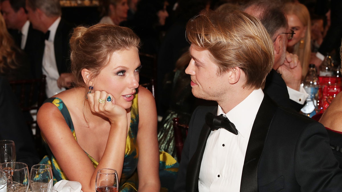 Taylor Swift looks at Joe Alwyn with her hand resting on her face at the Golden Globe Awards