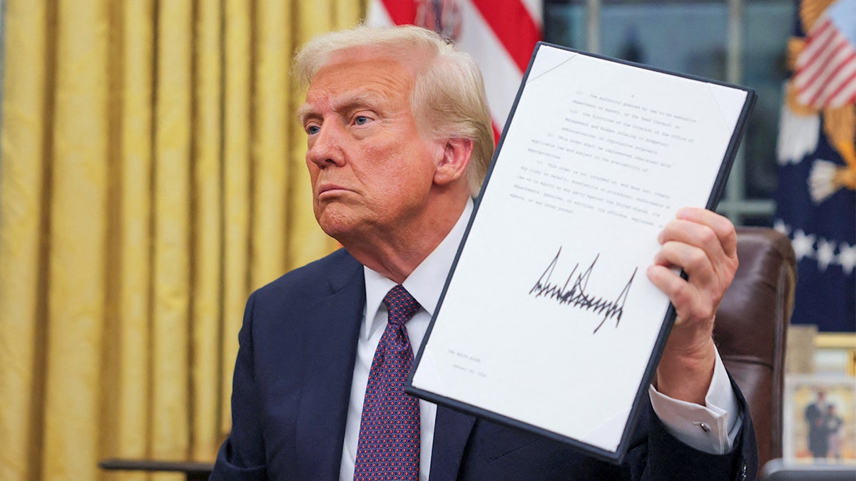 President Donald Trump holds a signed document