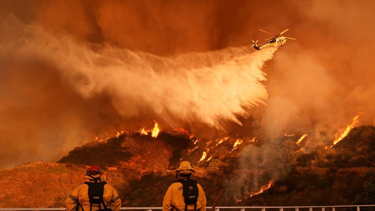 Los equipos de bomberos vieron un helicóptero arrojar agua en el fuego de Palisads en Mandevil Canyon en Los Ángeles el sábado 5 de enero de 2021. (AP Photo/Ja C Hong)