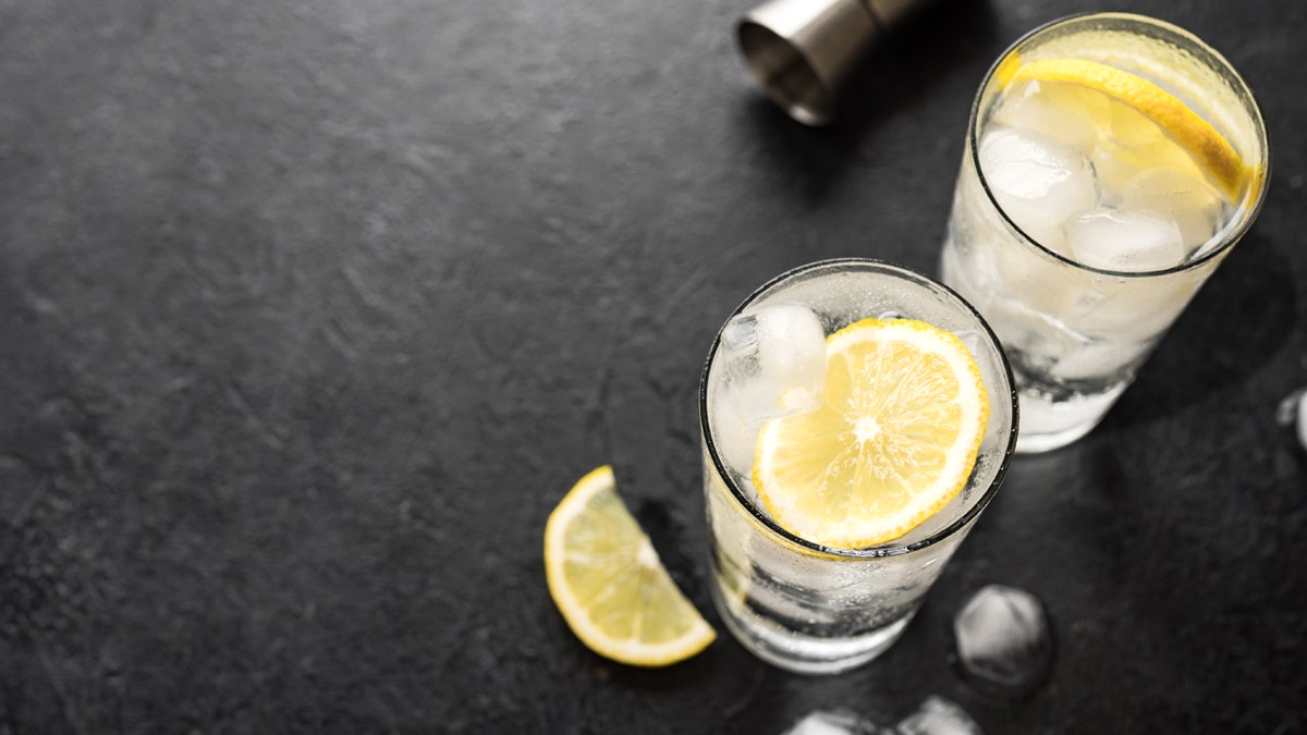 Vodka is in two glasses with ice cubes and lemons.