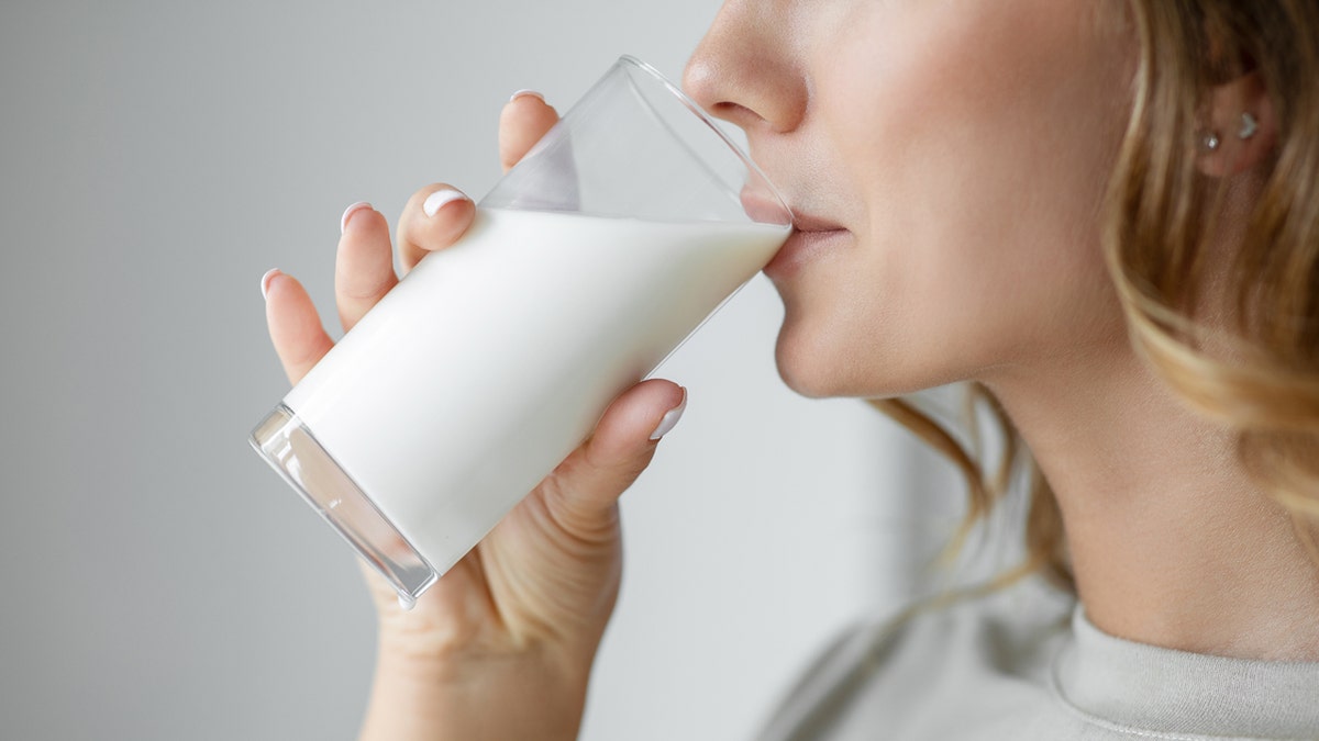 A woman drinks milk from a glass.