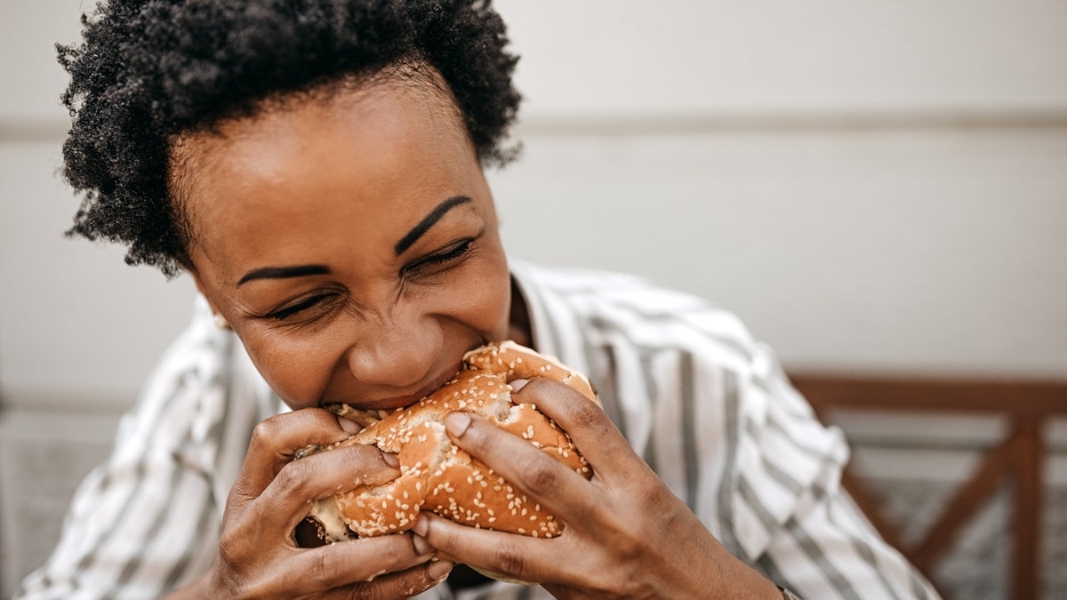 A woman enjoys burgers.