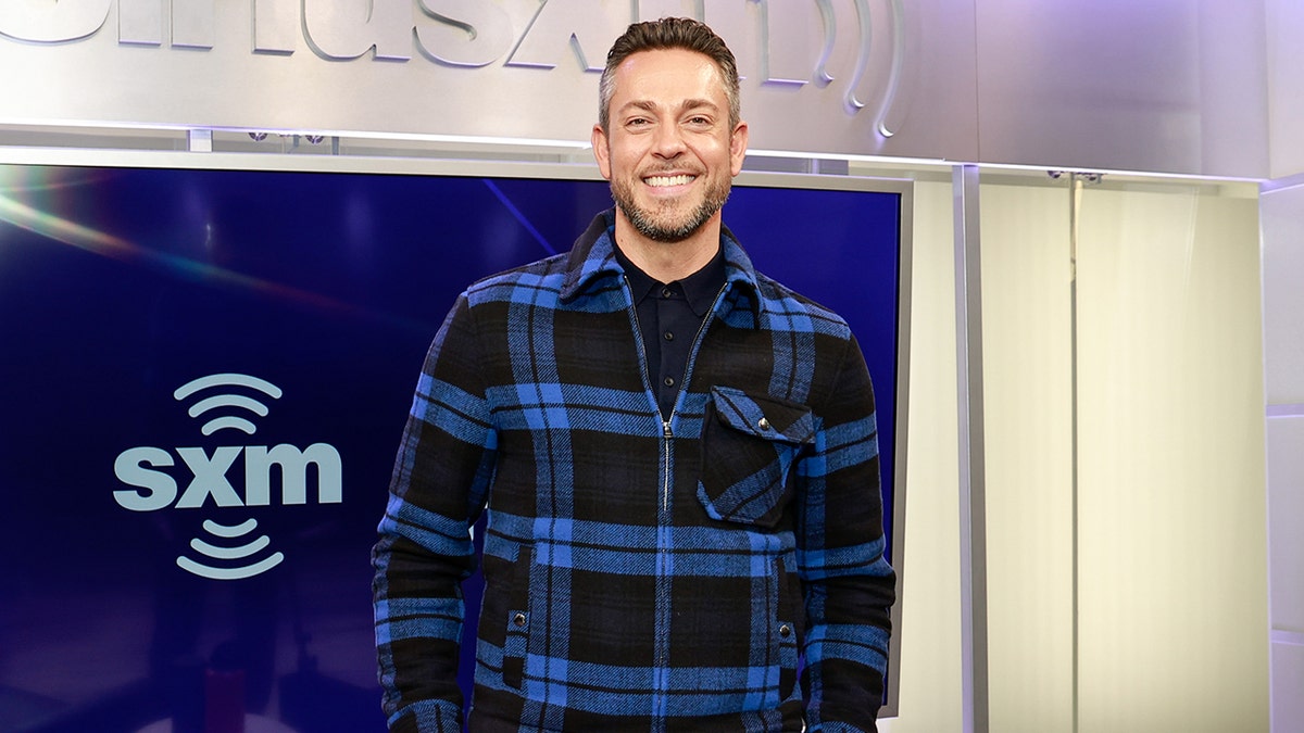 Zachary Levi berdiri di depan papan nama SiriusXM