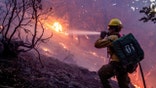 The wind whips embers while a firefighter battles the fire in the Angeles National Forest near Mt. Wilson as the wildfires burn in the Los Angeles area, during the Eaton Fire in Altadena, California, Jan. 9, 2025.