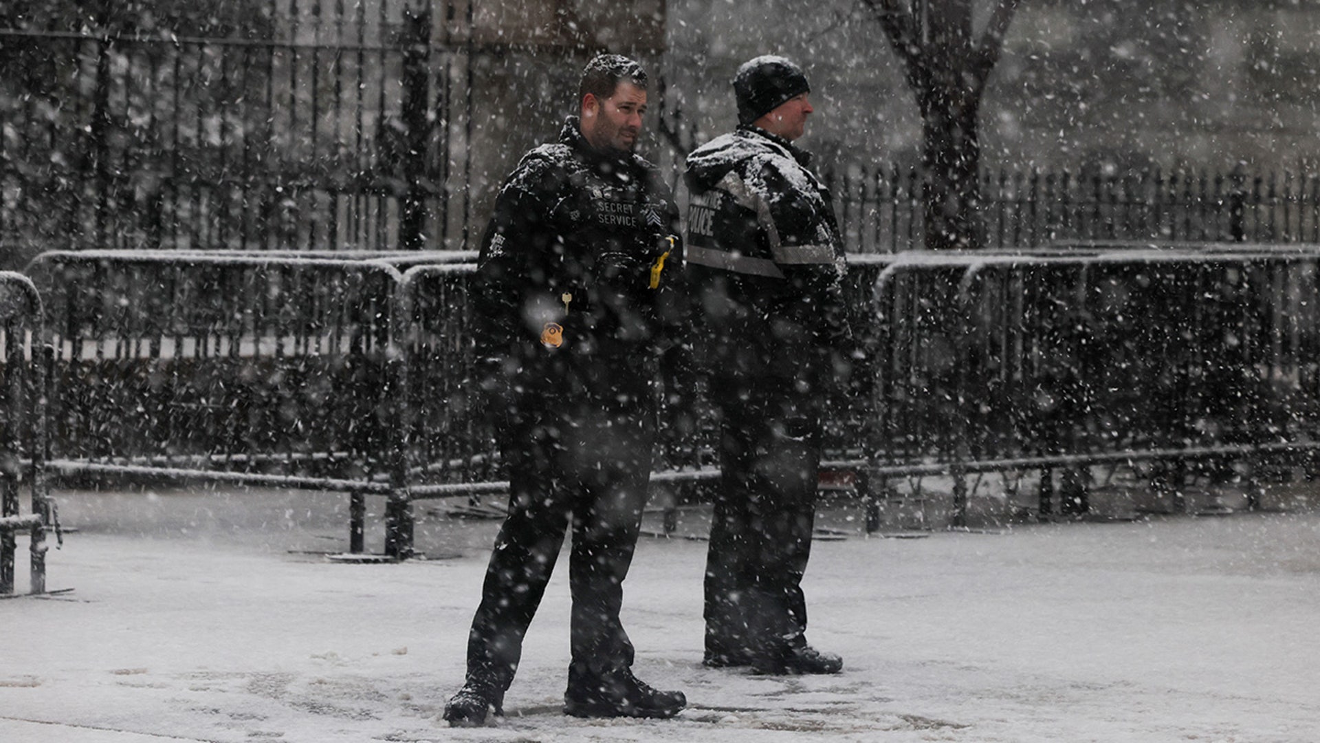 Secret Service officers stand during a snowstorm outside of the White House as they guard the departure of U.S. President-elect Donald Trump to a rally