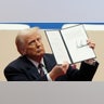 President Donald Trump holds up an executive orders after signing it