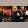Comedian Jeff Ross smiles in a black suit holding a cup of coffee walking into the Rotunda of the U.S. Capitol ahead of the inauguration