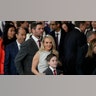Mike Fisher stands behind his wife Carrie Underwood in a gray dress who holds onto her son Isaiah