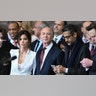 Lauren Sánchez in a white blazer and busty lace white bra/top stands beside Jeff Bezos in a dark suit and dark red tie at the inauguration