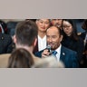 Lee Greenwood in a blue/turquoise plaid jacket sings into the microphone ahead of the inauguration