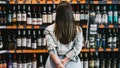 A woman stands with her hands behind her back as she faces a large selection of wines on shelves. - Fox News