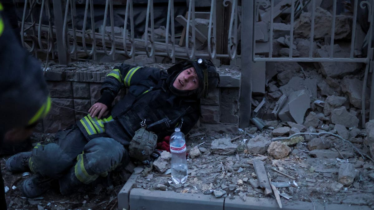 A rescuer rests after works at a site of apartment buildings hit by a Russian air strike, amid Russia's attack on Ukraine, in Kherson, Ukraine