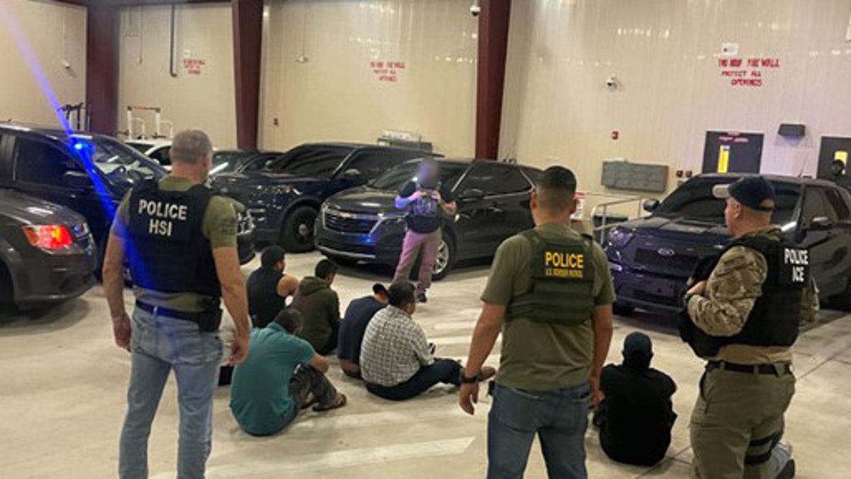 ICE agents seen from behind with detained migrants on ground