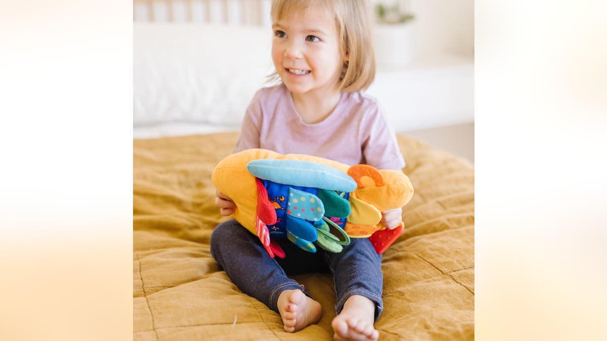 Encourage your baby to play with a crinkly, bright toy. 