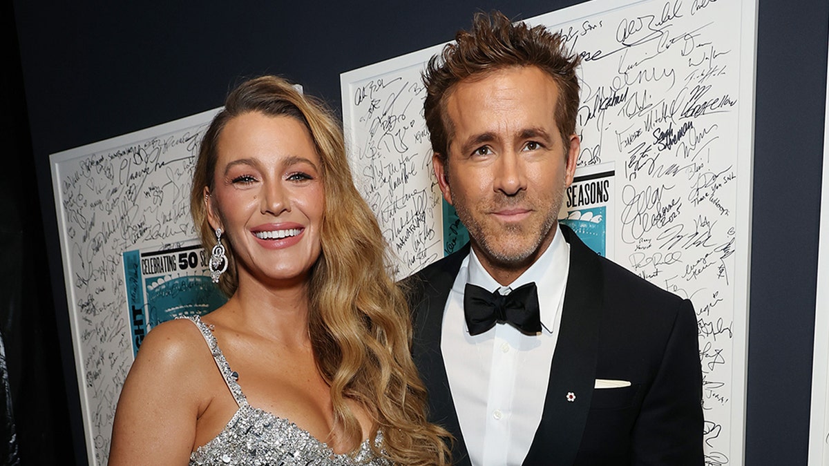 Bake Lively Smiles dalam gaun perak berkilau di sebelah suaminya Ryan Reynolds.