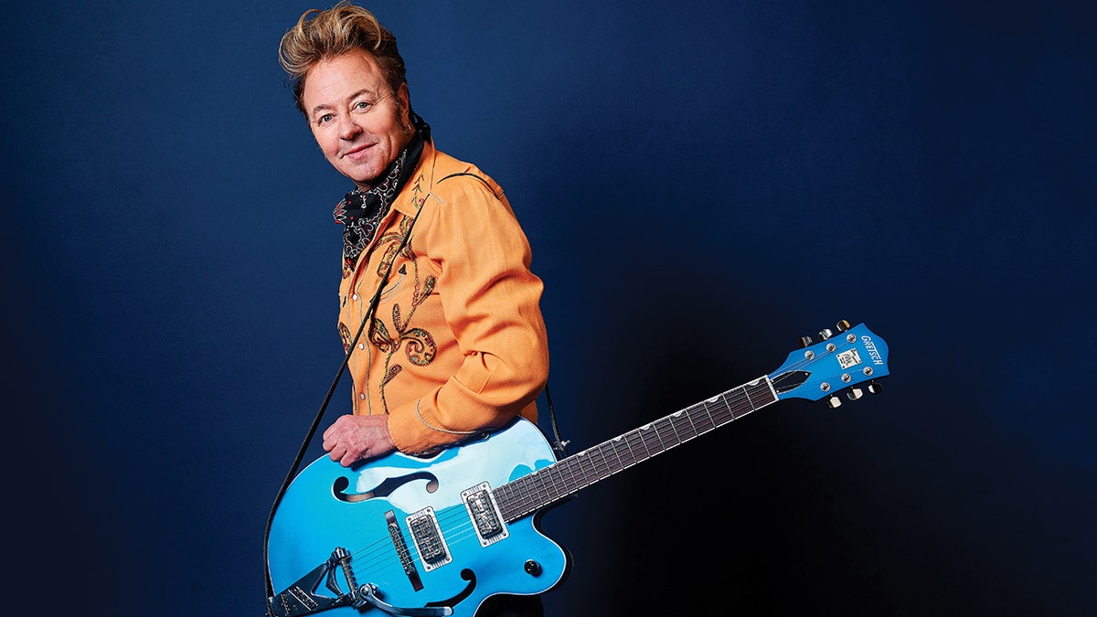 Brian Setzer posing with a blue guitar