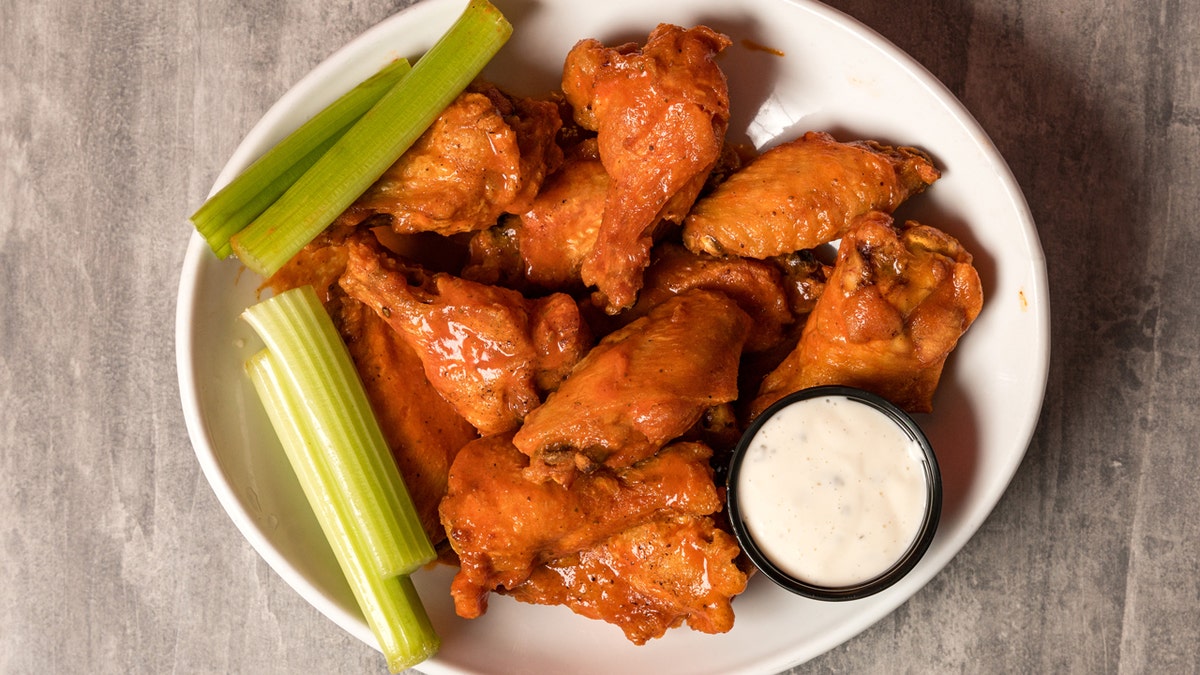 Buffalo wings with celery and ranch dressing connected  a plate.