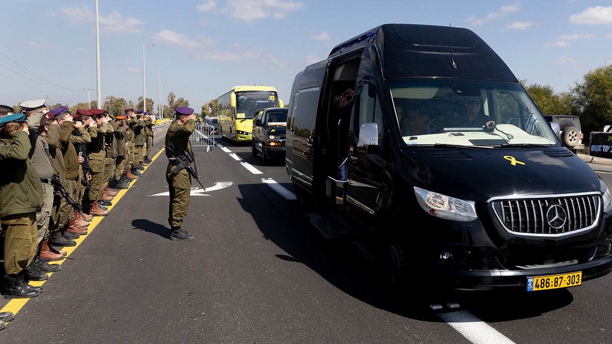 Soldiers salute as the funeral procession carrying caskets of Shiri Bibas, Kfir Bibas and Ariel Bibas pass by in Israel