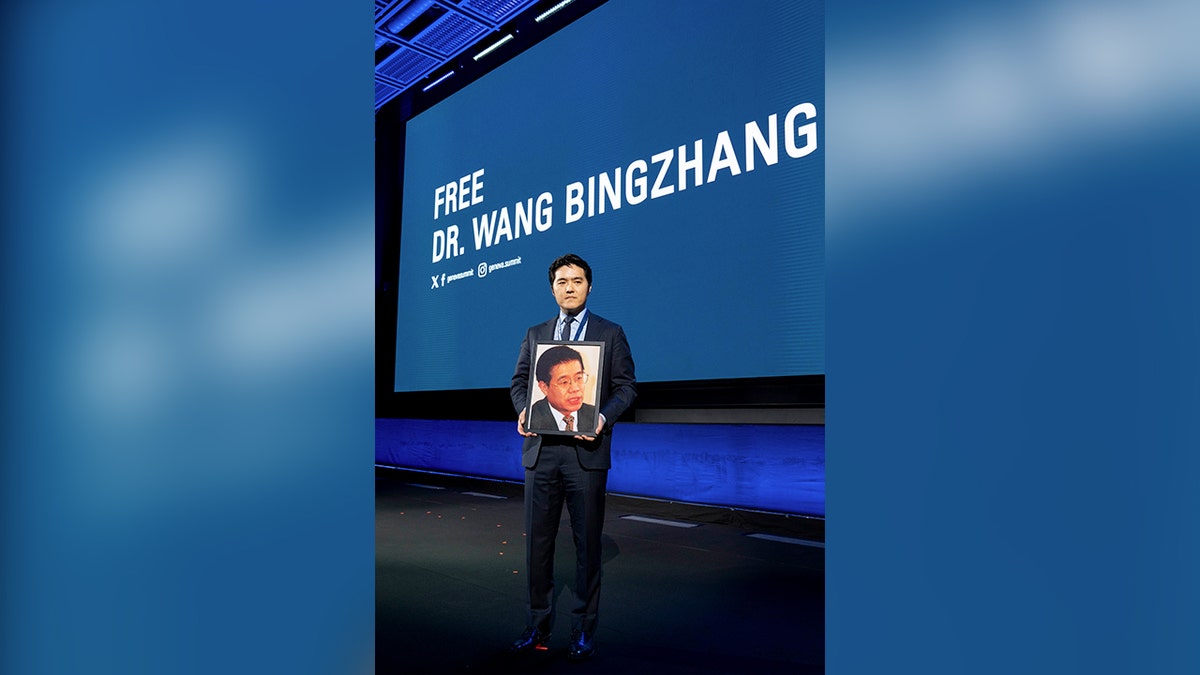 Times and Yang holds a picture of his father, Chinese prisoner, Dr. Wang Bingzang