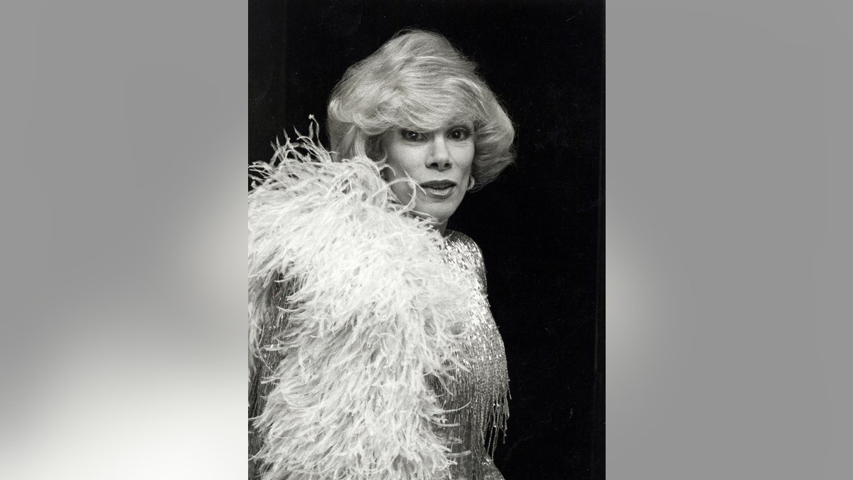 Joan Rivers sosteniendo una boa blanca.