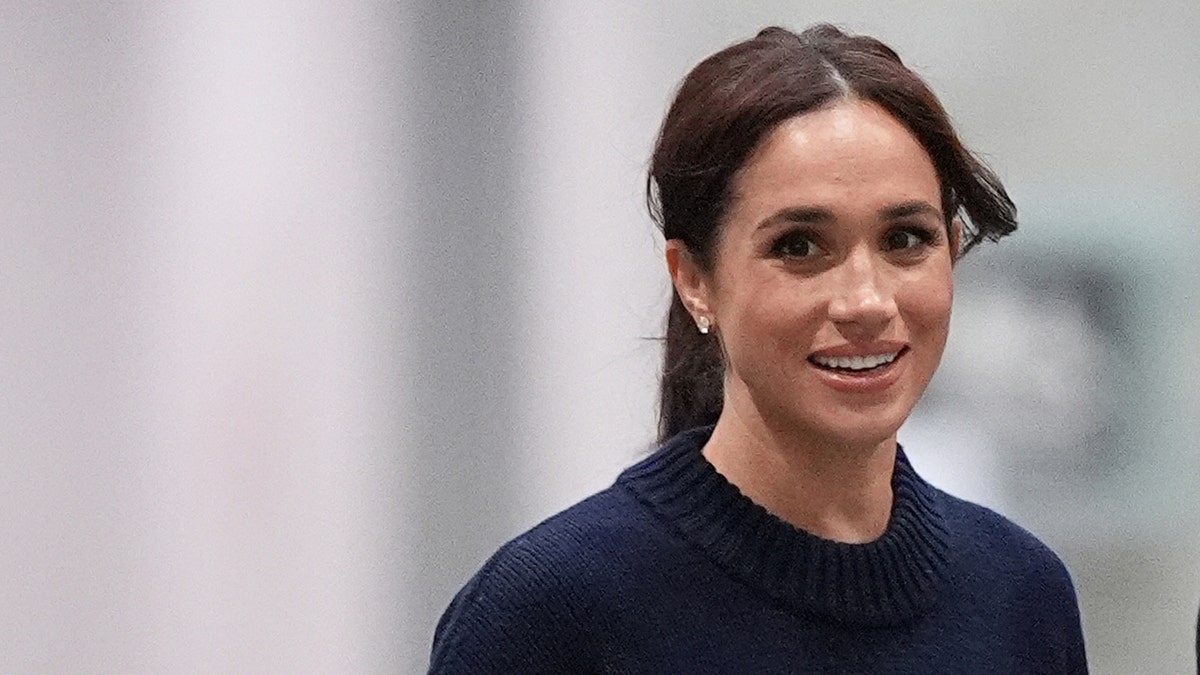 A close-up of Meghan Markle wearing a dark blue sweater.