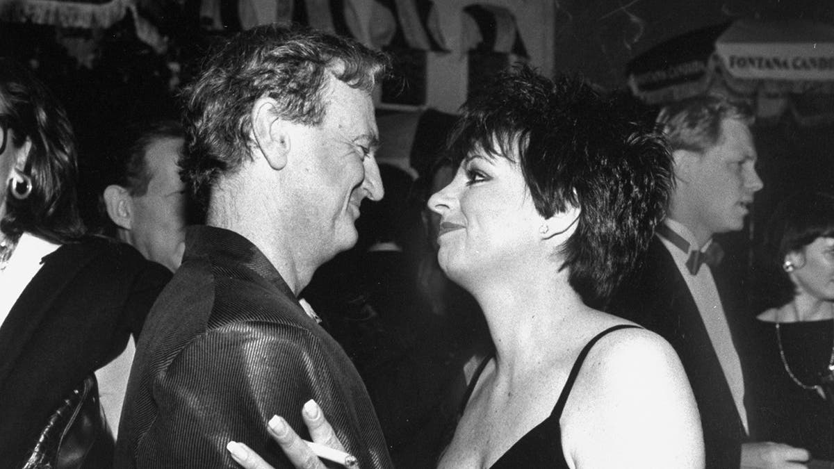 Liza Minnelli looking adoringly at Peter Allen wearing a black spaghetti strap dress.