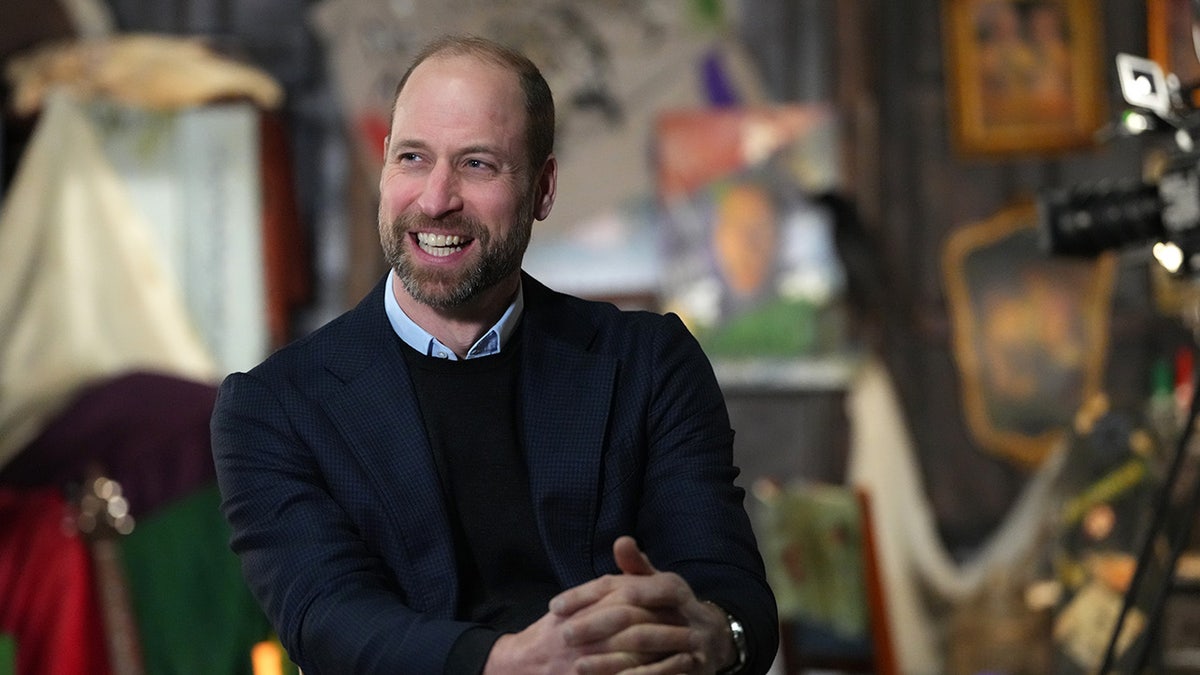 Prince William smiling in the distance wearing a blue formal attire