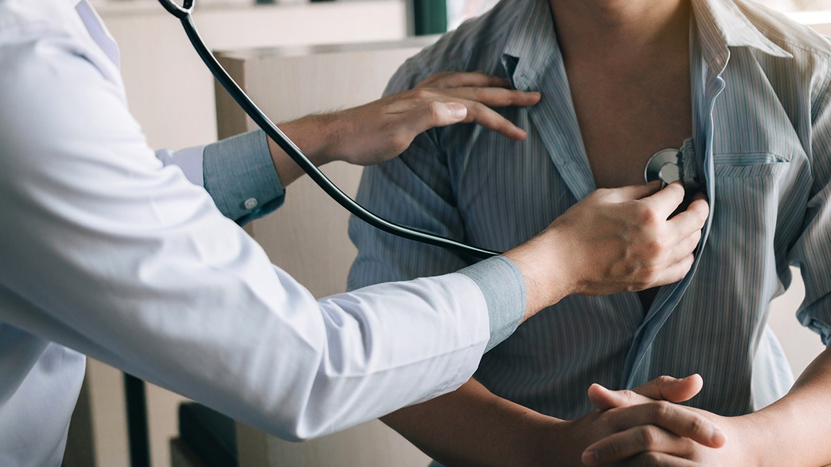 Doctor listening to person's chest with stethoscope.