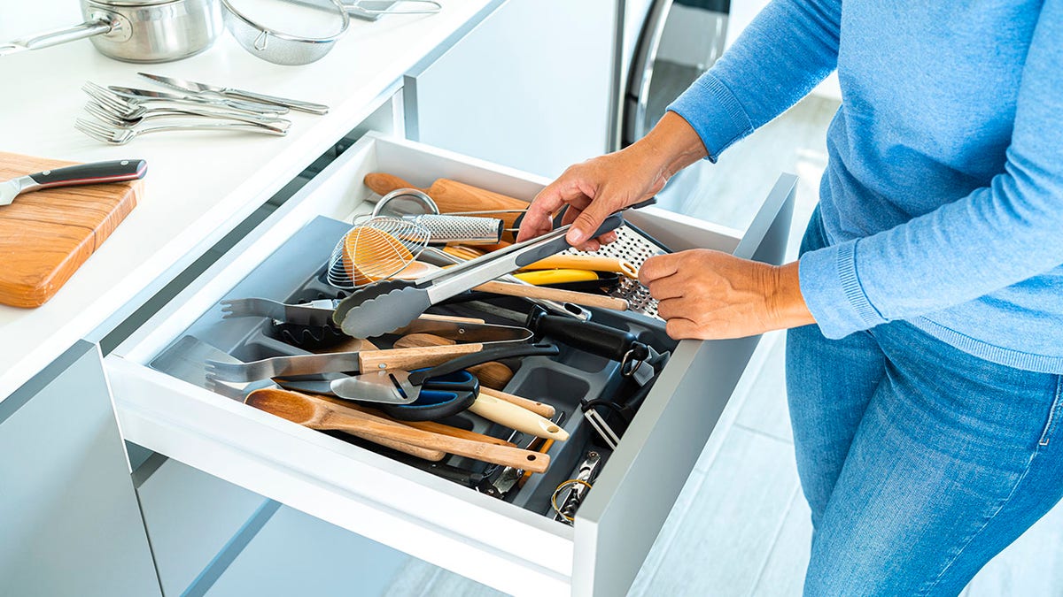 La mujer está organizando un cajón en contenedores de cocina.