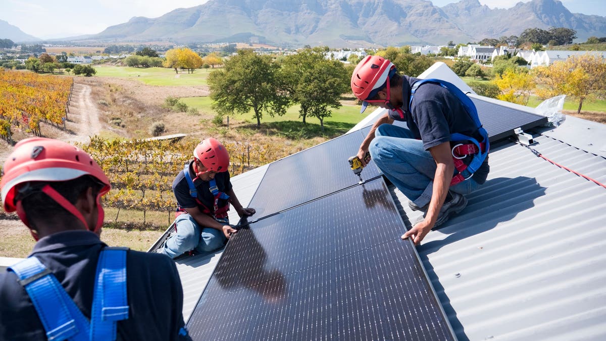 A team of workers install brackets for solar panels on the roof of a house in Cape Town, South Africa