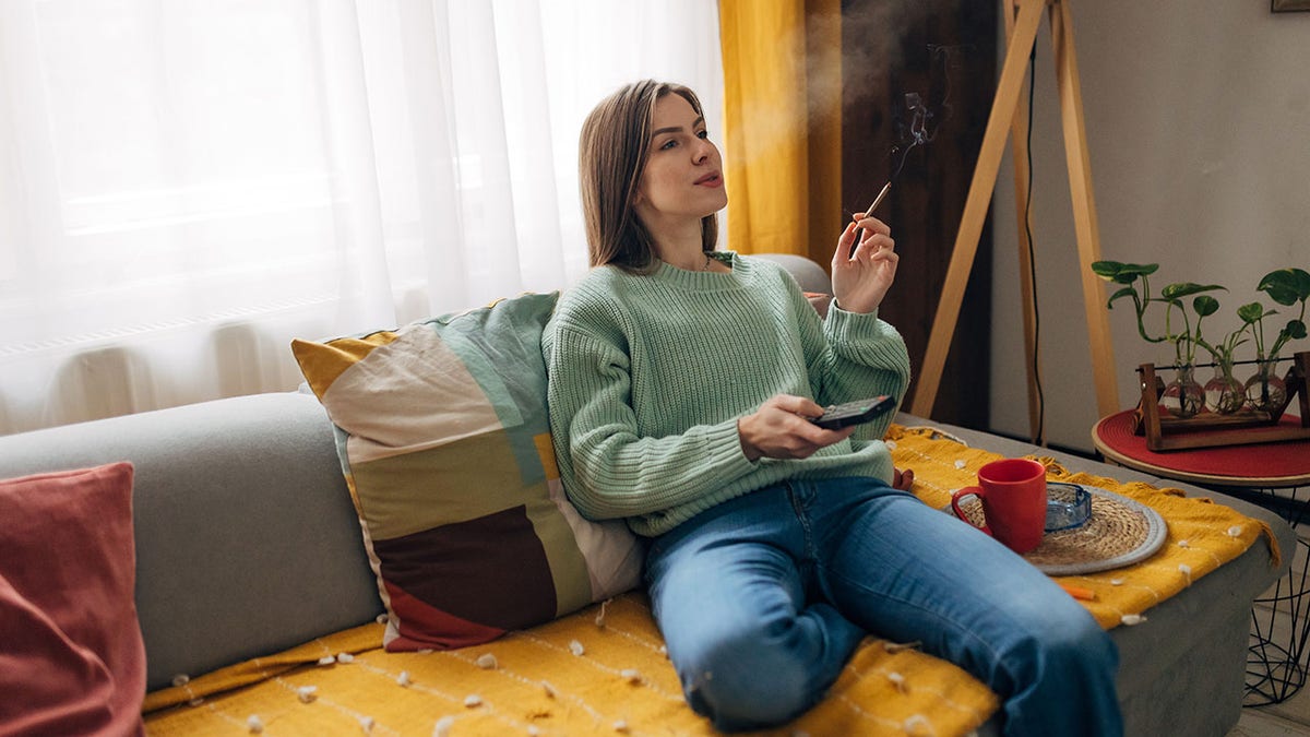 woman relaxes at home smoking a joint