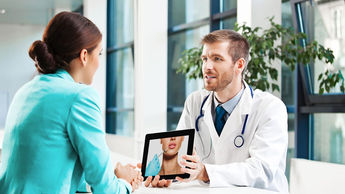 A male doctor talking with female patient about plastic surgery