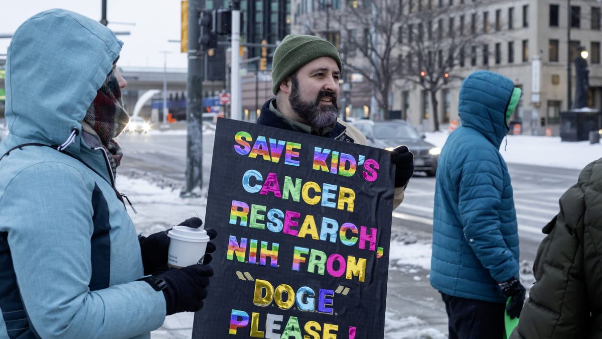 AND "There are no kings on the day of the President" The protest was shown on February 17, 2025 in Detroit in response to what they say are the undemocratic action of President Donald Trump and Elona Musk. Elliot Stephens carries a sign of cancer exploration. His teenage daughter has brain cancer and is currently part of a clinical trial.