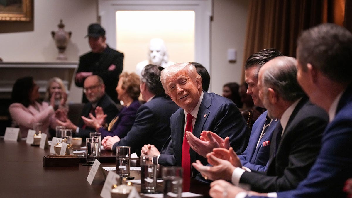 Trump está sentado na mesa durante a reunião do gabinete