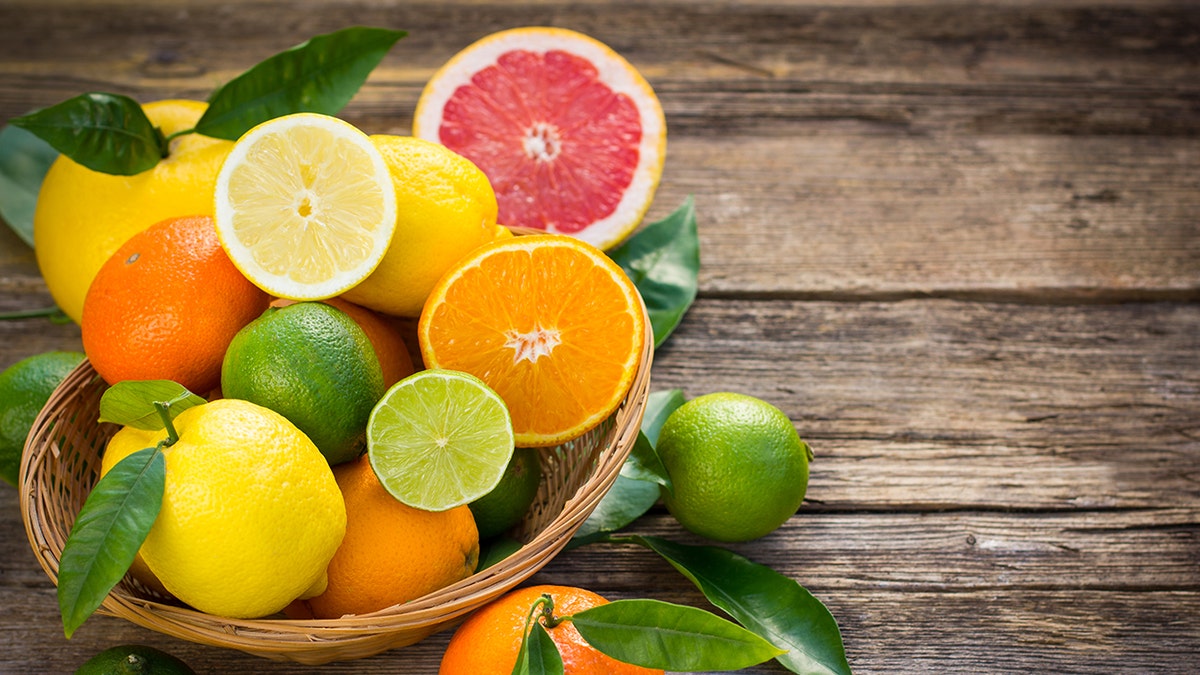 An assortment of citrus fruits in a basket on a table.