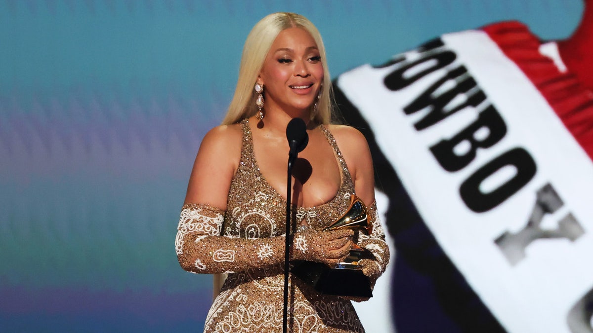 Beyoncé stands on stage holding Grammy award