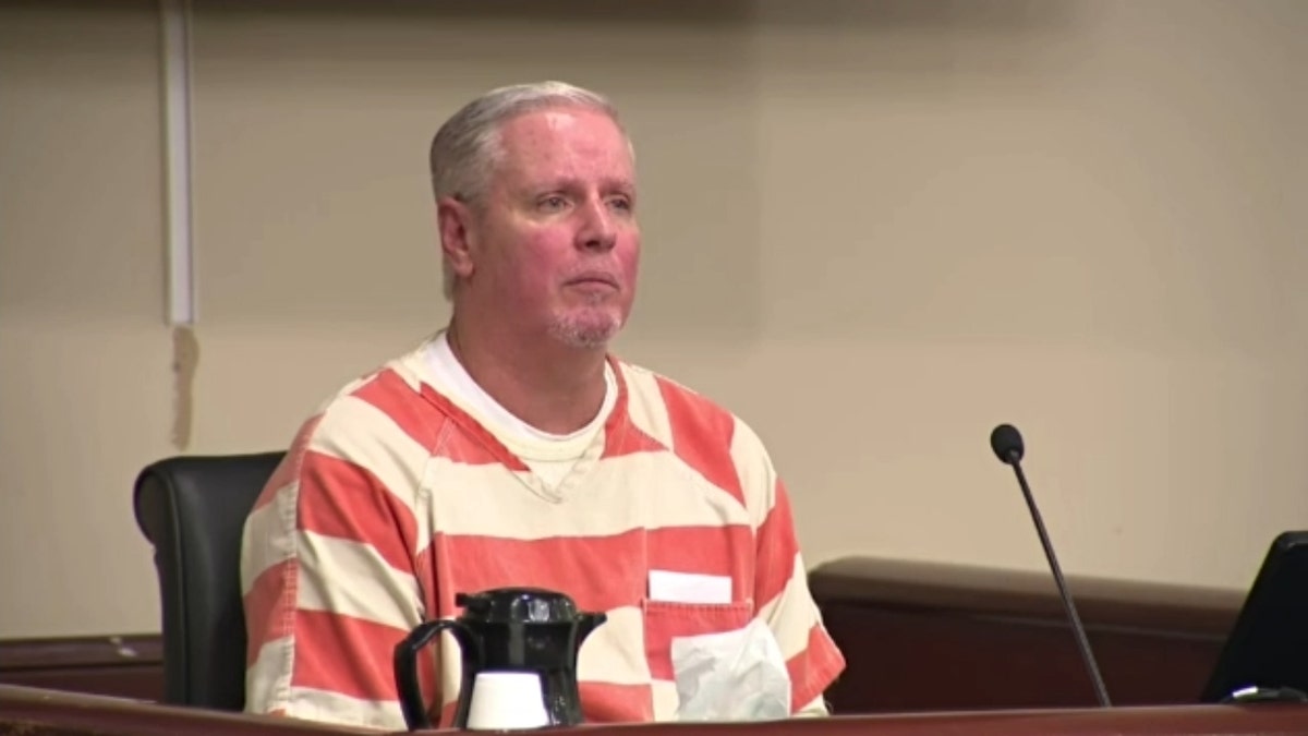 Colin Gray wearing an orange-and-white jumpsuit in court