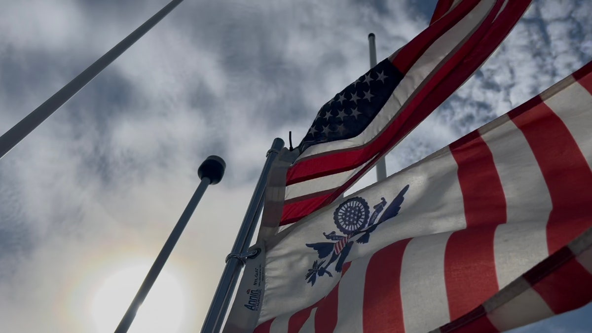 Strong wind blows American flag and US Coast Guard on board Rio Grande 