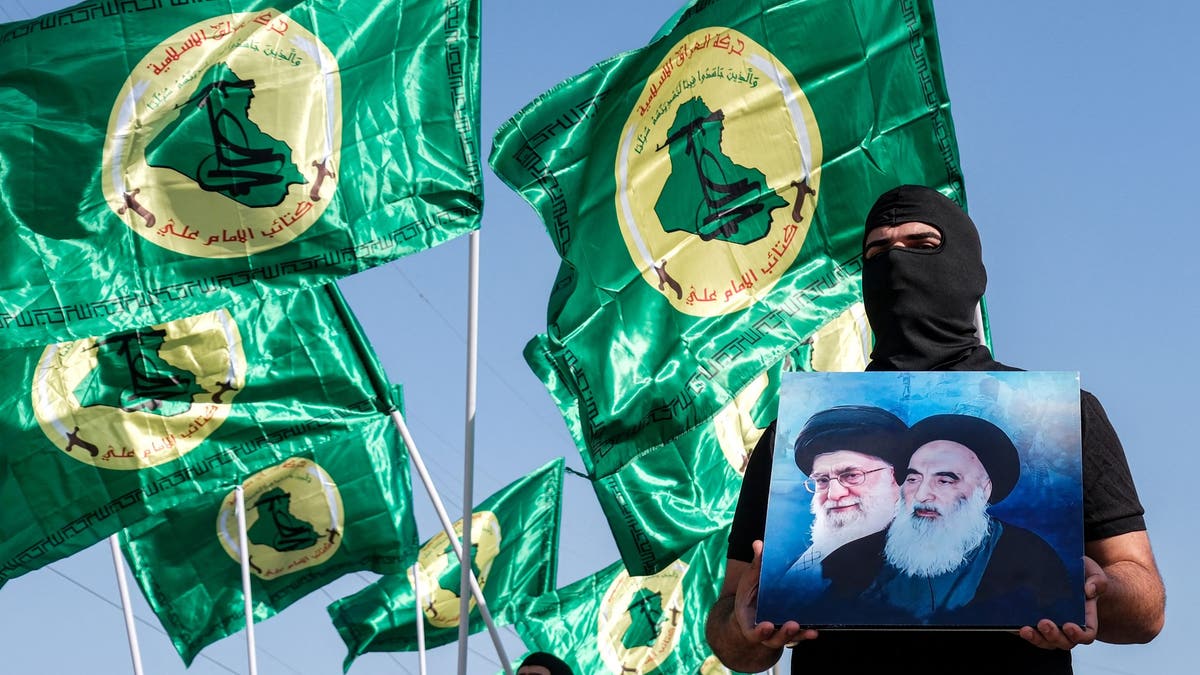 Member of the Islamic movement of Iraq holds photos of Iranian leaders.