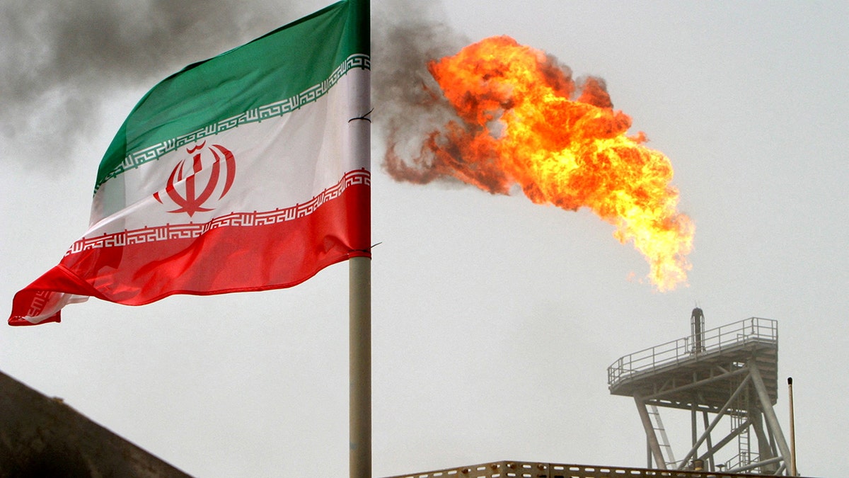 gas flare on an oil production platform is seen alongside an Iranian flag in the Gulf