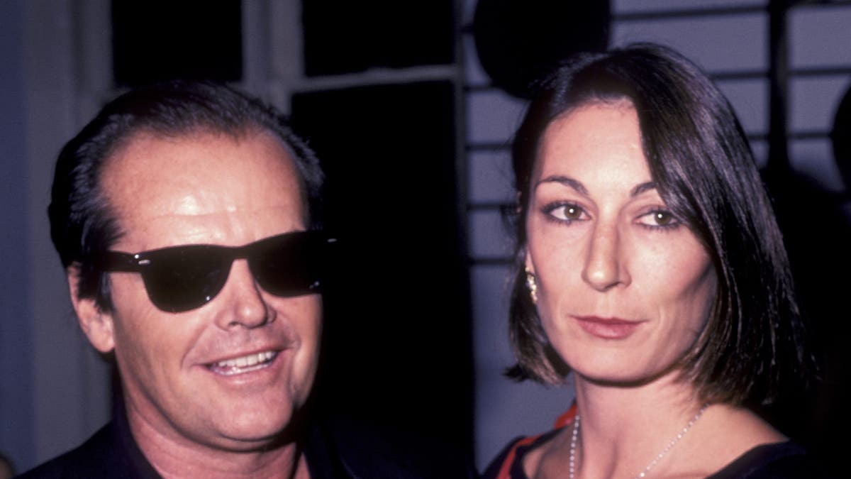 Jack Nicholson in sunglasses with a serious appearance of Anjelica Huston