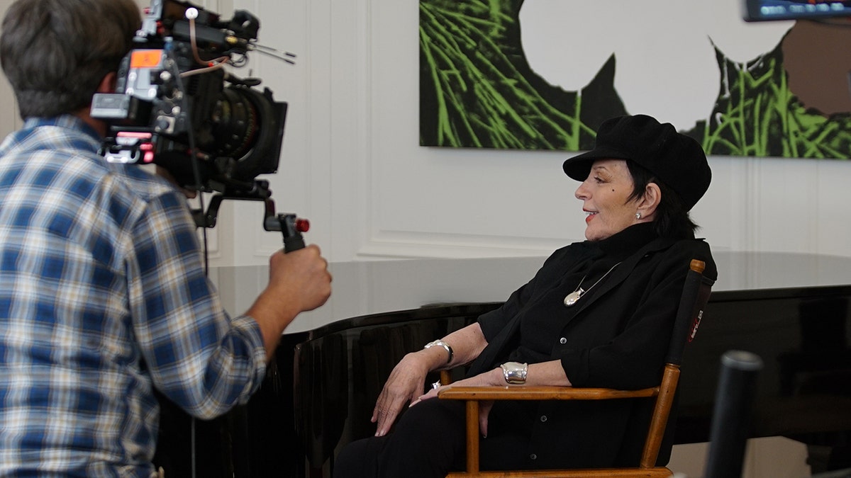 Liza Minnelli speaking to a camera as she wears all black.